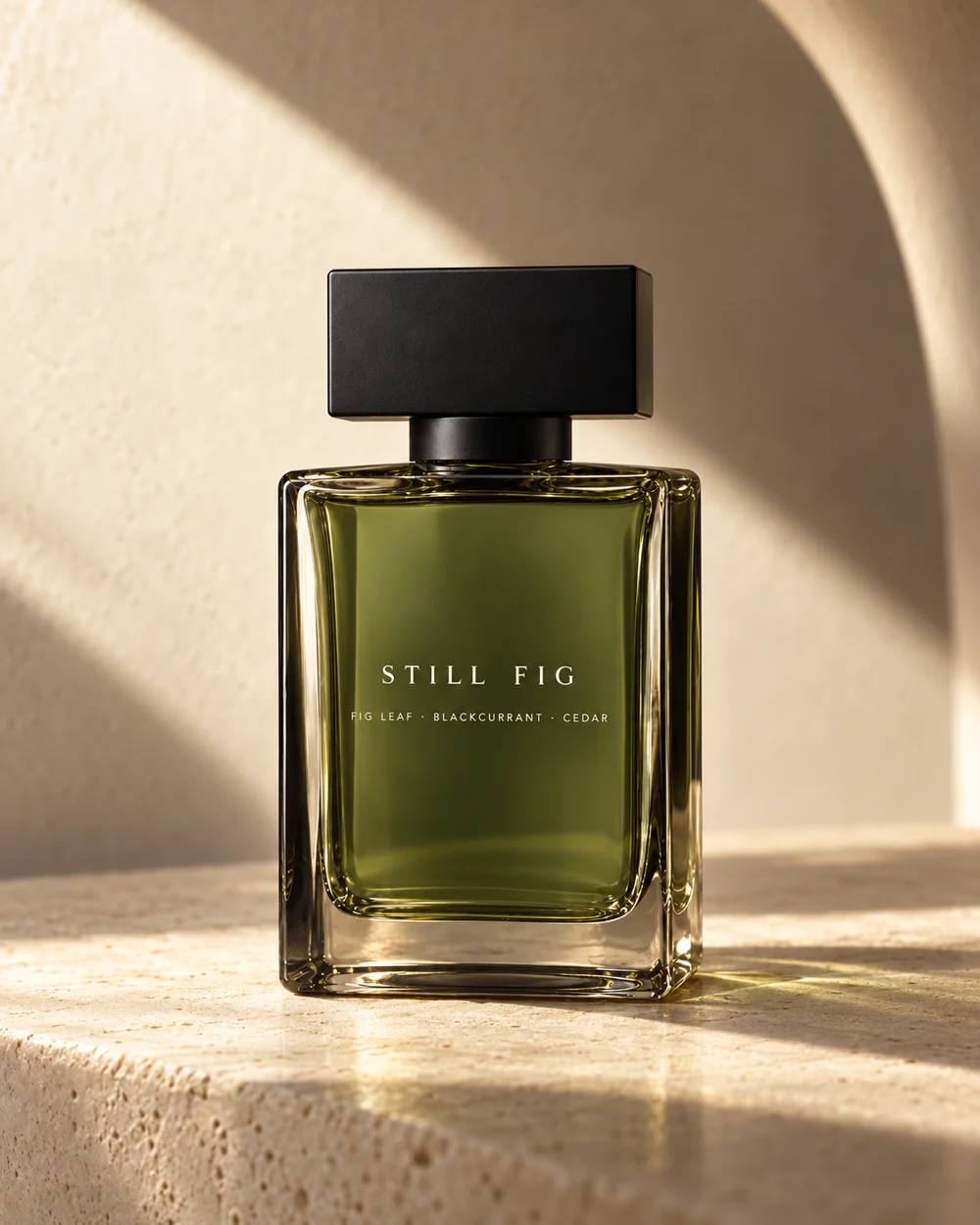 Still Fig perfume in olive-green glass on sunlit limestone